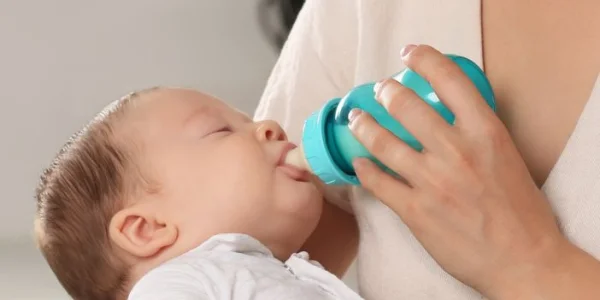 Infant receiving formula milk from a bottle